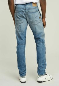 Vaaleansiniset farkut slim fit -mallissa, joissa on hieno haalistuminen, viisi taskua ja nahkainen logo-ommel vyötäröllä. Yhdistetty valkoisiin tennareihin.