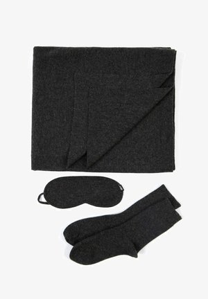 Dunkelgraue Decke, Augenmaske und Socken aus weichem Material. Decke ordentlich gefaltet, zeigt eine glatte Textur; die Accessoires sind farblich abgestimmt.