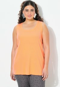 Oranje mouwloos topje met een ronde hals, ribbelstructuur en een losse pasvorm. Gecombineerd met grijze broek met luipaardprint.