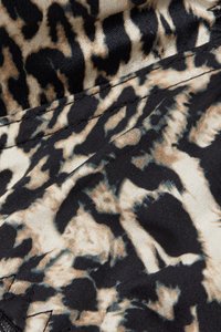 Tkanina w panterkę z gładką fakturą w odcieniach czerni, beżu i jasnego brązu. Abstrakcyjny wzór z ciemnymi akcentami na jasnym tle.