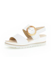 Sandalias blancas con dos correas anchas y un hebilla redonda de madera. Plantilla acolchada sobre una suela clara en cuña, con detalles texturizados.