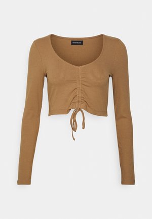 Brun ribstrikket cropped top med lange ærmer, rund halsudskæring samt justerbar rynket front, bundet ved taljen.