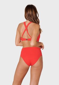 Red bikini set with a cross-back design and high-waisted bottom. Smooth, stretchy fabric with minimal stitching details.