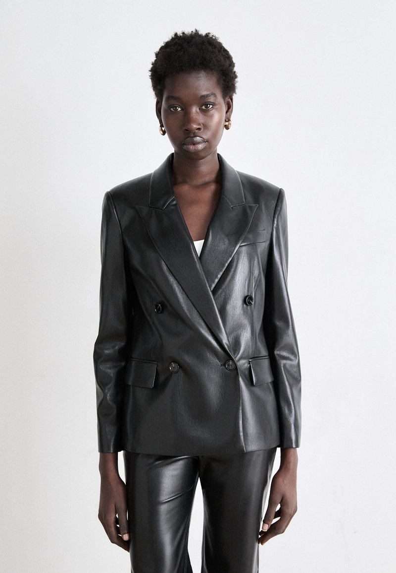 Blazer doppiopetto in pelle nera con revers a punta, finitura testurizzata e bottoni decorativi. Vestibilità sartoriale con due tasche a toppa.