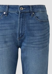 Tmavomodré džínsy z denimu s vyblednutou textúrou, s okom a gombíkovým zapínaním, piatimi vreckami a decentným prešívaním.