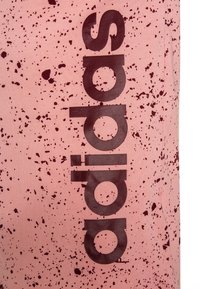 Rosa tyg med ett prickigt mönster i mörkare nyanser; har stora "adidas"-loggor i mörkbrunt. Slät textur, vertikal orientering.