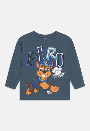 Tumesinise pika varrukaga T-särk, millel on koomiksikoer politsevormis, koos erksate tekstidega "HERO" ja "HIGH PAW!" julgete, värviliste tähtedega.