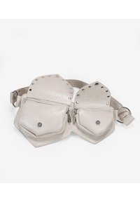 Riñonera de cuero beige con dos bolsillos con cremallera, forma hexagonal, superficie texturizada y acentos de tachuelas plateadas a lo largo de los bordes.