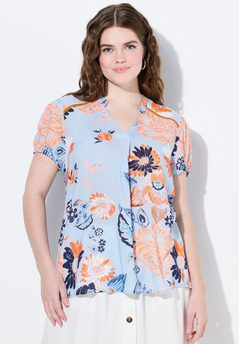 Blusa a maniche corte in tessuto azzurro chiaro con motivo floreale arancione e blu navy, dotata di scollatura a V e vestibilità ampia.