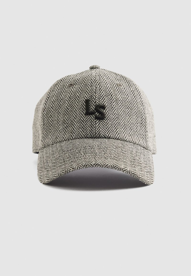 Gorra de espiga gris con un logo negro "LS" en la parte frontal, cuenta con una visera curvada y un tejido texturizado. Incluye una correa trasera ajustable.