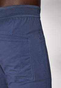 Tumedate bluud lühikesed püksid, millel on tekstureeritud elastne vöökoht, küljetaskud ja kontrastsed õmbluse detailid. Materjal näib kerge ja vastupidav.