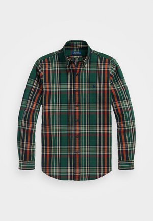 Chemise à manches longues boutonnée avec un motif à carreaux vert, marine, orange et crème et un col, posée à plat sur un fond blanc.