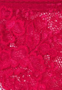 Tissu en dentelle rouge à motif en forme de cœur avec des détails complexes, texture légère et finition légèrement brillante.
