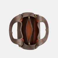 Barna bőr kézitáska két kerek fogóval, nyitott teteje belső cipzáras zsebet és belső rekeszeket mutat.