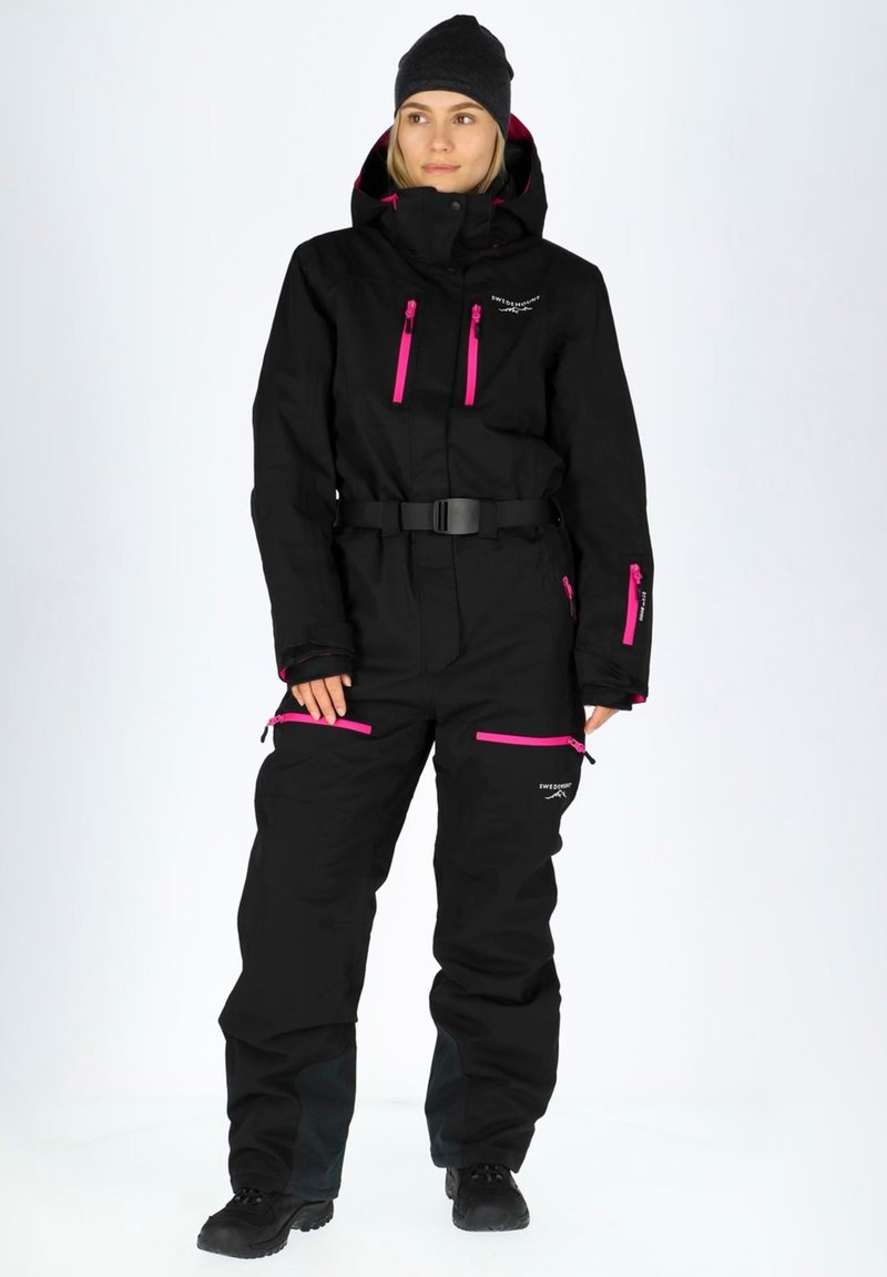 Black snow suit with pink zippers and accents. Features a belted waist, high collar, and multiple zippered pockets. Includes adjustable cuffs.
