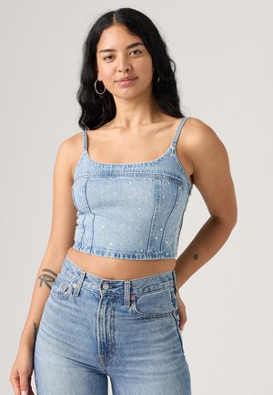 Lichtblauwe denim crop top met dunne bandjes, met een getailleerd ontwerp en verspreide versieringen. Gecombineerd met high-waisted denim jeans.