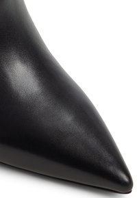 Tacco a spillo nero in pelle con punta affusolata, dalla texture liscia e silhouette elegante. Presenta una parte anteriore tapered e una finitura lucida.