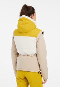 Šilta pūkinė striukė su geltonu kapišonu, baltu viršutiniu skyriumi ir pilkšvai ruda apatine dalimi. Savybės: elastinga juosmena ir aukštas apykaklė šilumai.