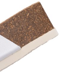 Nahaufnahme einer weißen Schuhsohle mit beiger Zwischensohle und strukturierter brauner Kork-Fußbett-Schicht.