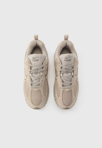 Μπεζ αθλητικά παπούτσια Nike με πάνελ από δίχτυ, δέσιμο με κορδόνια, επενδυμένο γιακά και θηλιά στο τακούνι. Λαστιχένια σόλα με υφή στη χάραξη.