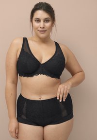 Zwarte kant beha met beugel en doorzichtig gaas, gecombineerd met bijpassende hoogris briefs. Beide hebben ingewikkelde bloemenpatronen.