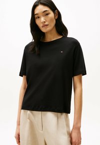 Sort T-shirt med korte ærmer lavet af blød bomuld, med rund halsudskæring og et lille mærke logo på venstre brystområde.