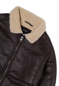 Giacca di pelle marrone con colletto in shearling beige, chiusura frontale con zip e tessuto texture. Presenta cuciture e un'etichetta interna con logo.