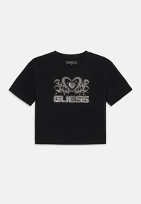 Svart kortärmad t-shirt i bomull, med ett silverhjärta och blommönster med "GUESS"-logotypen i fet stil i mitten.