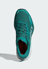 Scarpa da ginnastica turchese con tomaia in rete, punta rinforzata e suola sagomata. Presenta dettagli grigi e una linguetta con marchio.