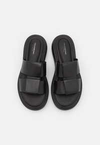 Paire de sandales noires à enfiler avec larges brides en cuir et semelles rembourrées, portant la marque "Vagabond Shoemakers" à l'intérieur.