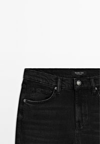 Jean en denim noir avec poches avant, passants de ceinture, bouton argenté et une étiquette de marque « Massimo Dutti » à la taille.