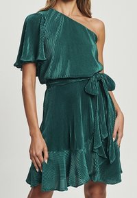 Robe une épaule en bleu canard avec texture plissée, courte manche à volants et taille ceinturée. Jupe fluide avec un ourlet à volants.