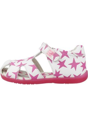 Sandalia blanca para niño pequeño con estrellas rosas, punta abierta, correa ajustable de velcro y suela rosa.