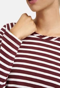 Bordeaux- und weiß gestreiftes langärmliges Shirt mit Rundhalsausschnitt und rohen Kanten, aus einem weichen, strukturierten Stoff gefertigt.