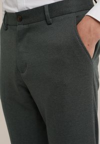 Texturerade grågröna byxor med slim fit, med flat front, fickor och brun knappstängning.