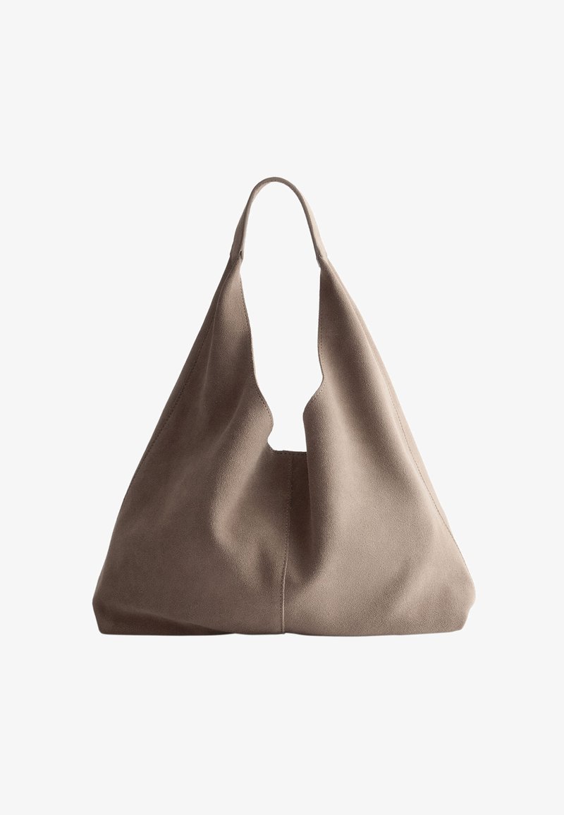 Sac hobo en daim beige avec une poignée profonde découpée. Texture douce et silhouette souple créent un design à la fois décontracté et moderne. Aucune quincaillerie visible.
