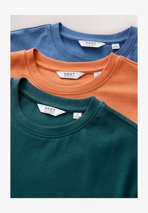 Kolm lühikeste varrukatega T-särki virnastatud. Värvid: türkiissinine, oranž ja sinine. Valmistatud pehmest kangast, ümara kaelusega ja siltidega "NEXT" sees. Regulaarsuurus.