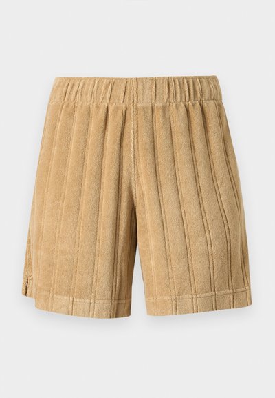 Shorts en tissu éponge marron clair avec coutures verticales, taille élastique et petites fentes latérales sur un fond uni.