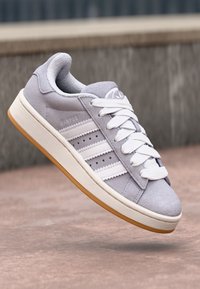 Light gray suede sneaker with white stripes and laces, rubber outsole, and embossed "CAMPUS" detail on the side. Flat, low-profile design.