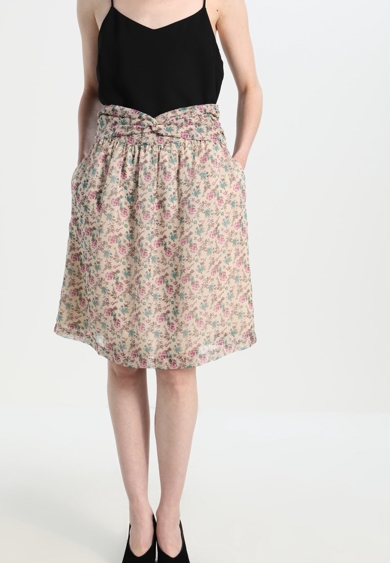 Falda floral con fondo beige, estampados en rosa y verde, cintura elástica y bolsillos. Tejido parcialmente transparente con una forma fluida.