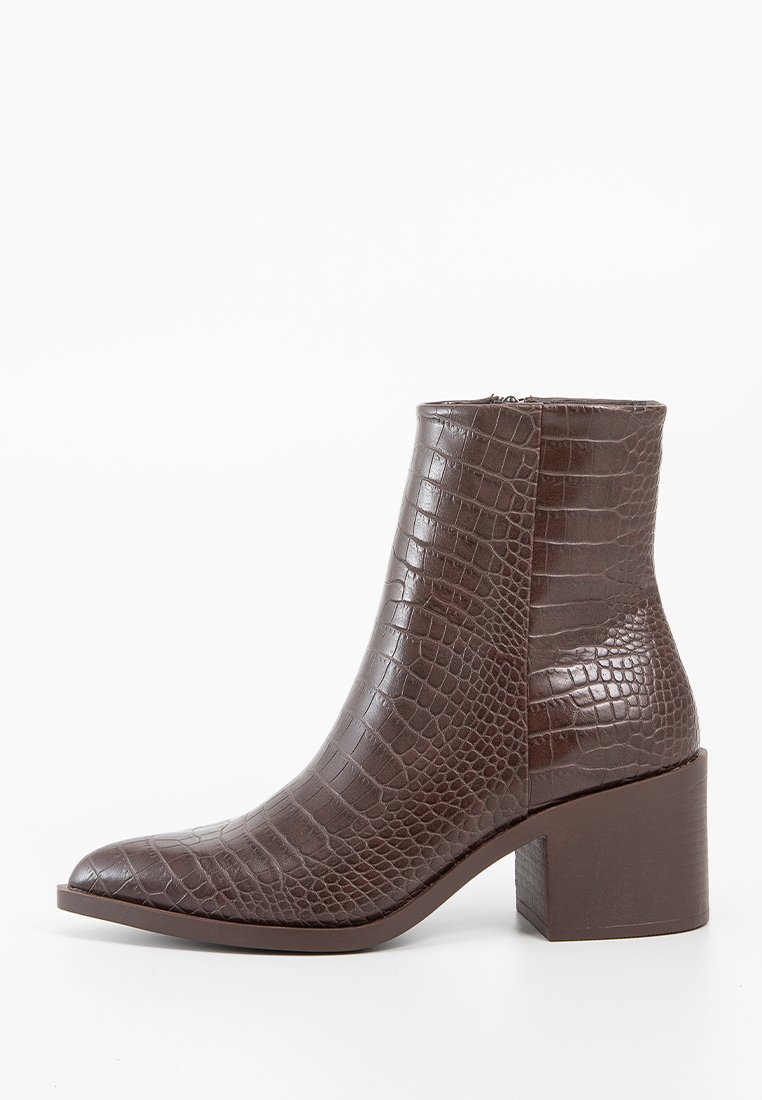 Stivali alla caviglia in finta pelle marrone con texture goffrata a croco, punta appuntita e tacco chunky. Chiusura con zip laterale per una facile vestibilità.