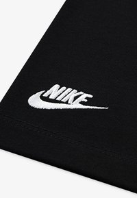 T-shirt en tissu noir arborant un logo Nike brodé en blanc. La texture est lisse avec une finition nette sur les bords.