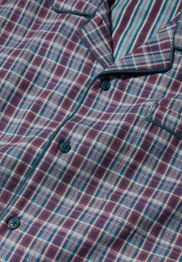 Camisa de pijama a cuadros en azul, púrpura y naranja. Tejido suave con un bolsillo en el pecho, ribete en contraste y botones azules.