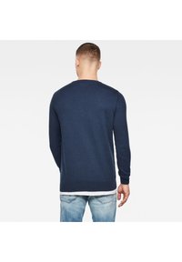 Námořnická modrá dlouhá mikina z pleteniny, s kulatým výstřihem a žebrovanými manžetami. Viditelné švy a přiléhavý střih.