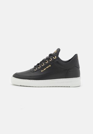 Zwarte leren sneaker met gouden oogjes en branding. Heeft een dikke witte zool met gekarteld design. Schone lijnen en minimalistische stijl.