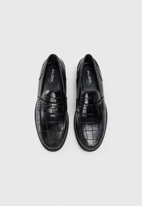 Loafers negri din piele texturată, cu un model în grilă. Vârf rotund, profil jos și detalii cusute în jurul marginii.