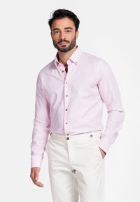 Lichtroze langemmouwshirt van katoen met een button-down kraag en bruine knopen, gecombineerd met witte broek.