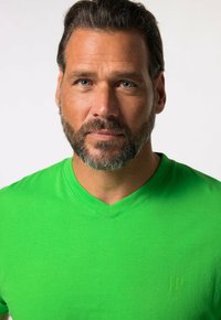 Camiseta verde de cuello en V hecha de algodón, con un logotipo sutil en el lado izquierdo, textura suave y un diseño ajustado.