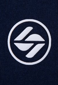 Navyblauer Strickstoff mit einem auffälligen weißen, kreisförmigen Logo, das stilisierte, überlappende Formen zeigt, die Wellen ähneln. Glatte Textur.