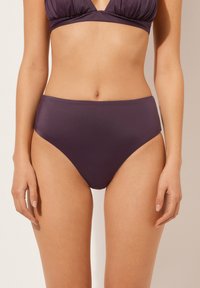 Hochgeschnittene Bikinihose in tiefem Lila, aus glattem Stretchmaterial mit nahtlosem Design und mittlerer Bedeckung, in einfarbiger Ausführung.